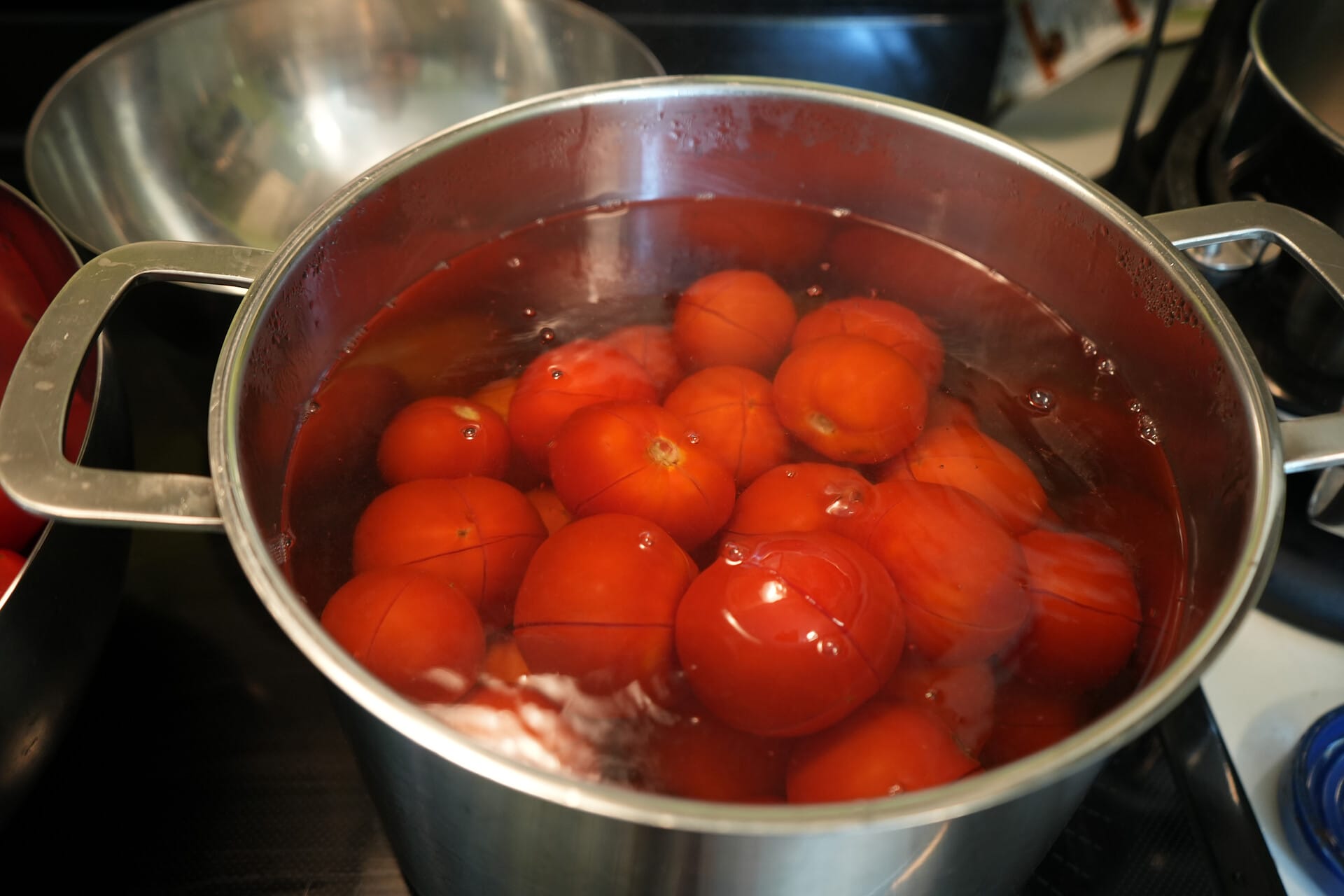 Scored tomatoes in a pot of water