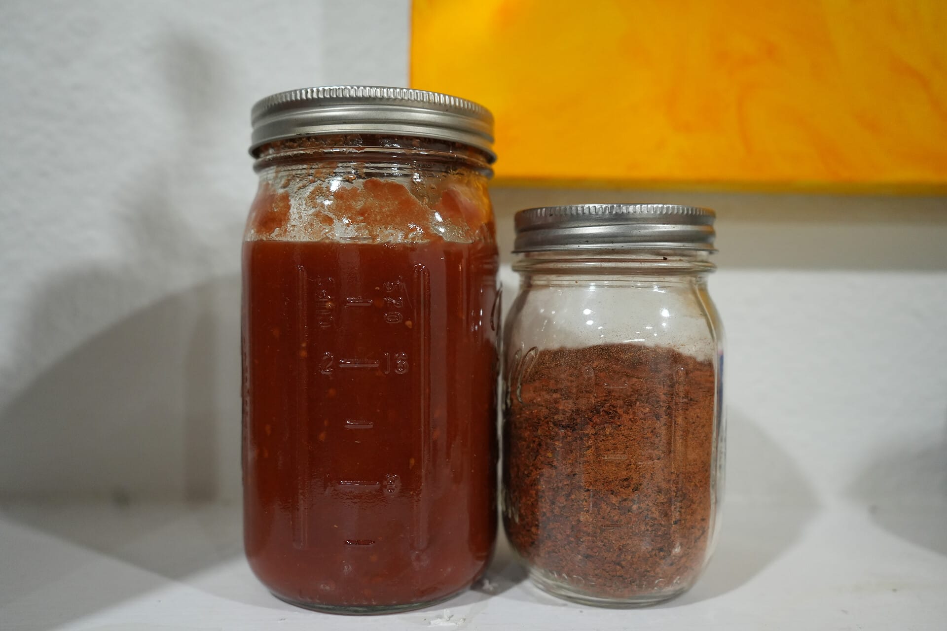 A jar of tomato sauce next to a jar of tomato powder